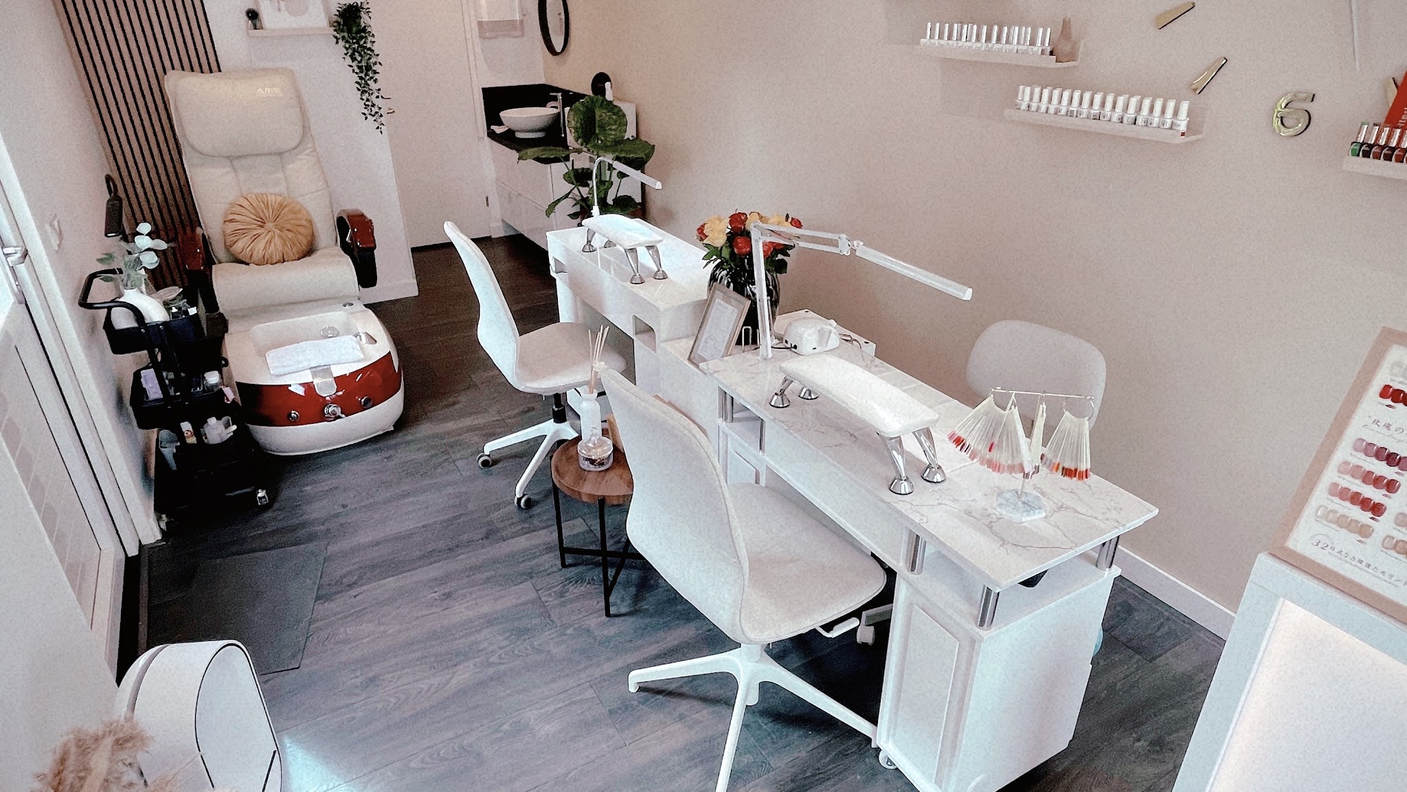 De studio: twee witte nageltafels, een pedicurestoel en wanden vol nagellak